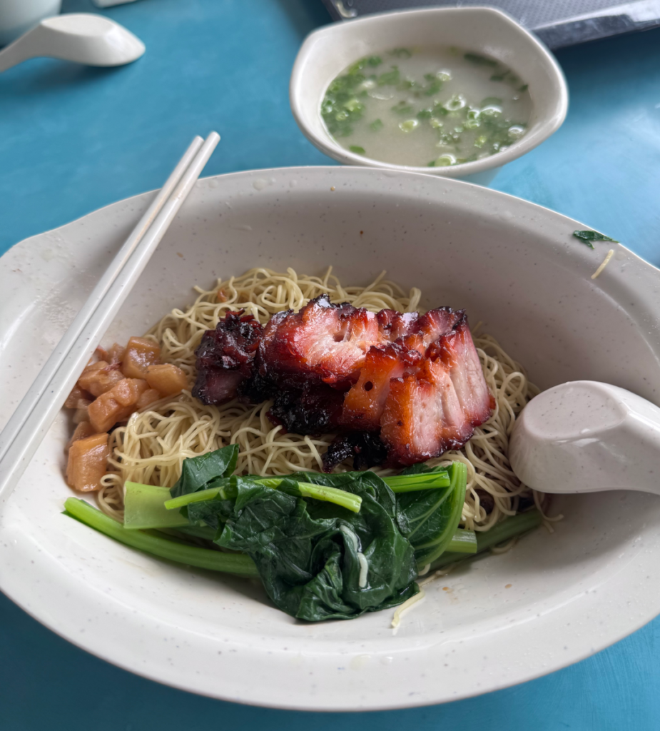 Chef Kang wanton mee before mixing, with charred char siew, crispy pork lard cubes and greens on egg noodles, and a bowl of wanton soup on the side