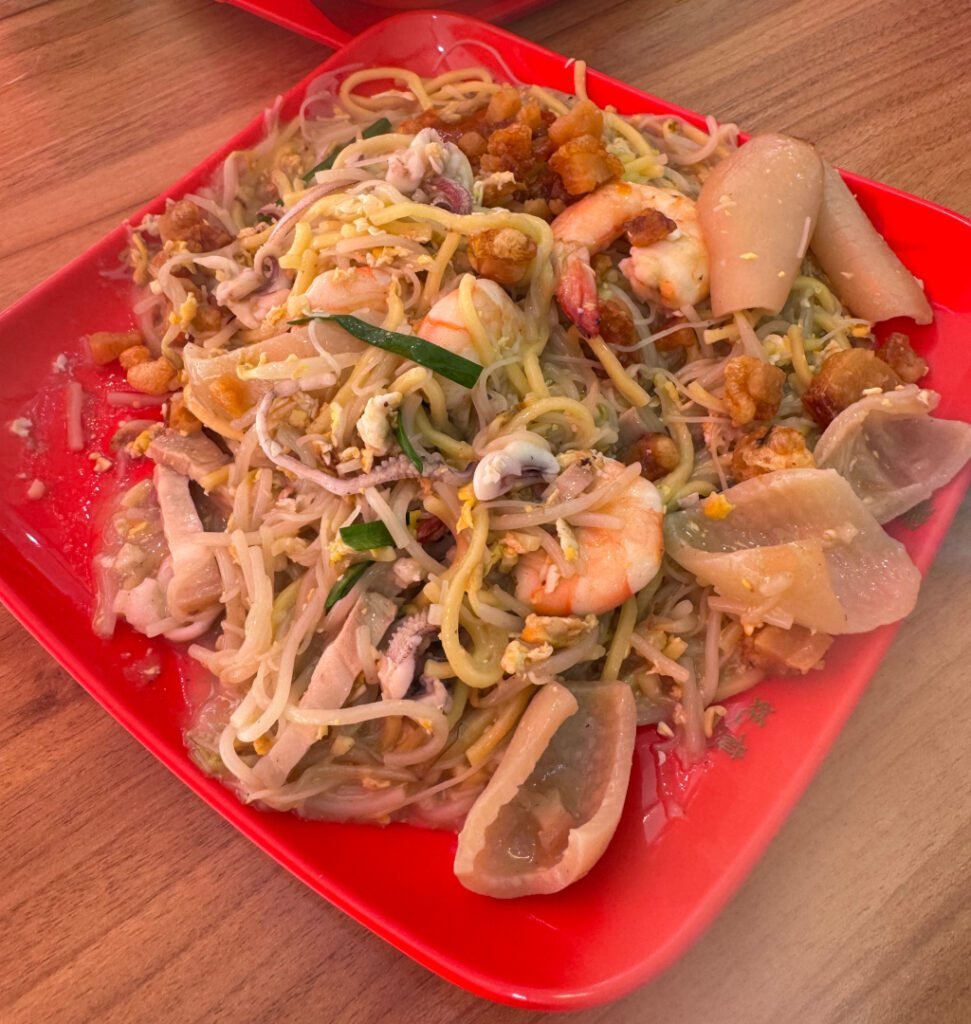 Plate of Fung Yi Hokkien Mee with prawns, squid, pig skin and pork lard on yellow noodles and bee hoon