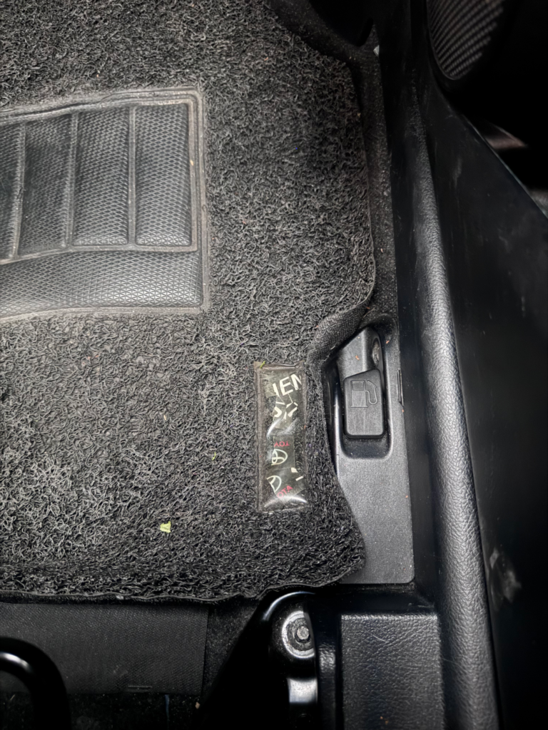 Fuel lid release lever on the floor beside the driver’s seat of a Toyota Sienta Hybrid